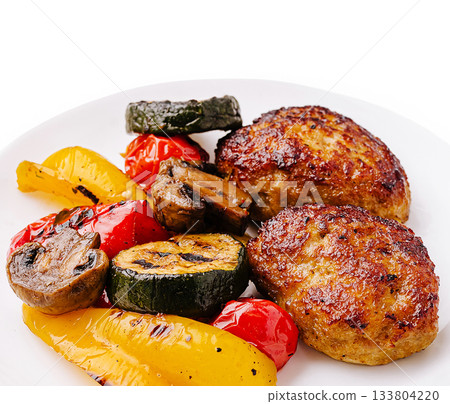 Delicious grilled meat patties served with colorful roasted vegetables Delicious grilled meat patties served with colorful roasted vegetables 133804220