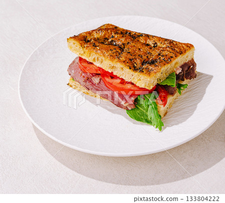 Delicious roast beef sandwich with fresh tomatoes and lettuce on a white plate 133804222