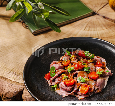 Fresh roast beef salad with cherry tomatoes and herbs on a rustic table 133804232
