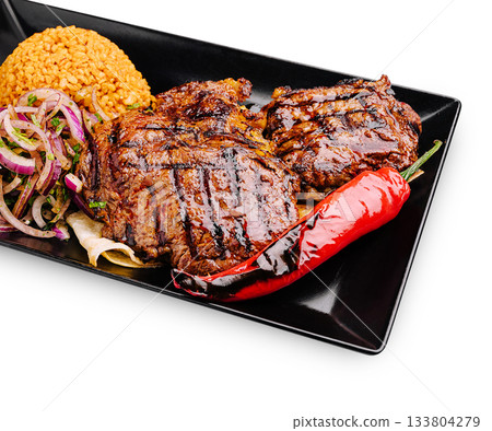 Delicious grilled steak with rice and vegetables served on a black plate Delicious grilled steak with rice and vegetables served on a black plate 133804279