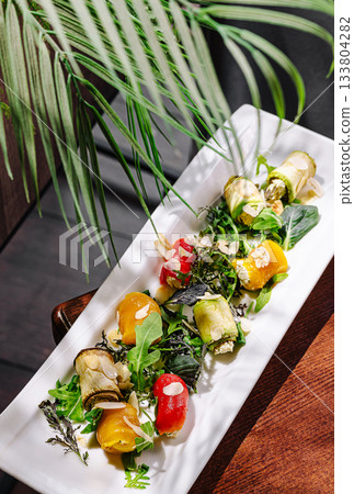 Colorful vegetable rolls with fresh greens on a white platter at a restaurant Colorful vegetable rolls with fresh greens on a white platter at a restaurant 133804282