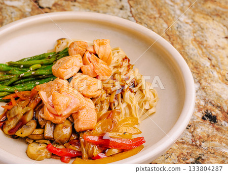 Delicious salmon bowl with vegetables and noodles on a marble surface 133804287