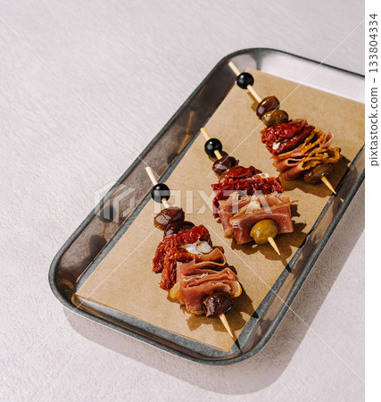 Delicious meat and olive skewers served on a stylish tray 133804334