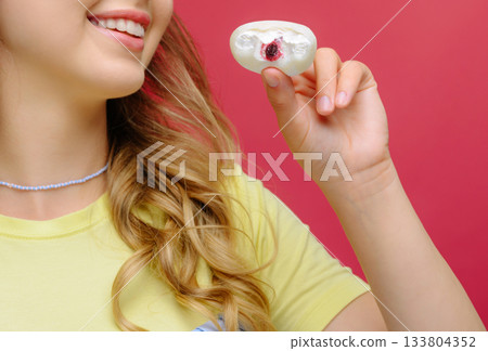 Young woman holding unique candy against bright pink background 133804352