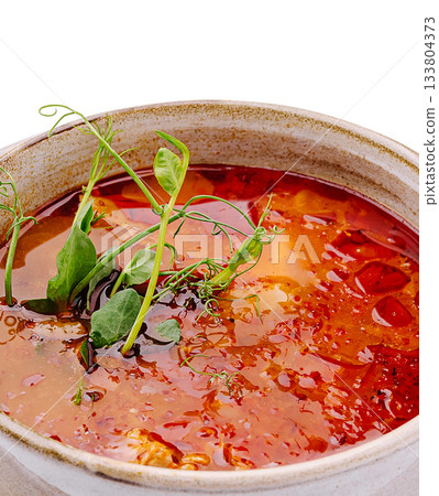 Warm bowl of spicy soup with fresh herbs and colorful ingredients for lunch 133804373