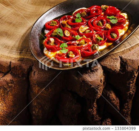 Freshly prepared roasted peppers garnished with nuts on a rustic wooden table 133804399