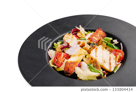 Grilled chicken salad served on a black plate with fresh vegetables 133804414