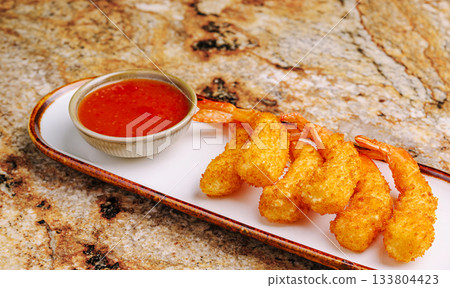 Delicious golden fried shrimp served with sweet dipping sauce on a plate Delicious golden fried shrimp served with sweet dipping sauce on a plate 133804423