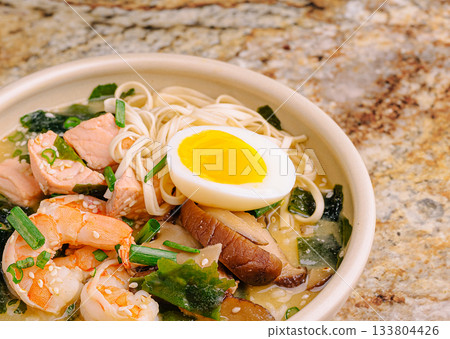 Delicious seafood noodle bowl with egg served in a cozy kitchen setting Delicious seafood noodle bowl with egg served in a cozy kitchen setting 133804426