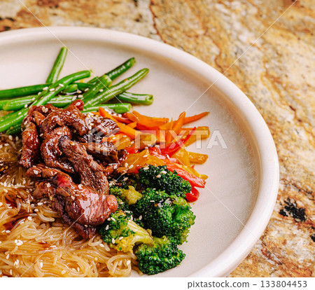 Colorful plate of stir-fried noodles with beef and fresh vegetables served 133804453