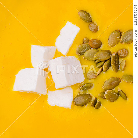 Creamy pumpkin soup topped with cheese and pumpkin seeds ready for tasting 133804574