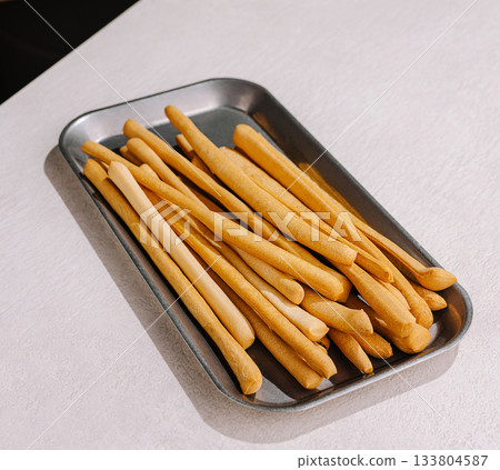 Baked breadsticks served on a metal tray ready for enjoyment at a meal Baked breadsticks served on a metal tray ready for enjoyment at a meal 133804587