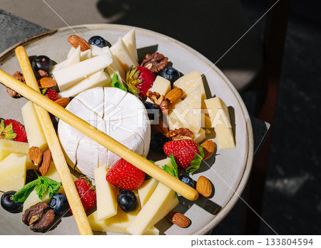 Cheese platter with fruits and nuts arranged beautifully on a plate 133804594