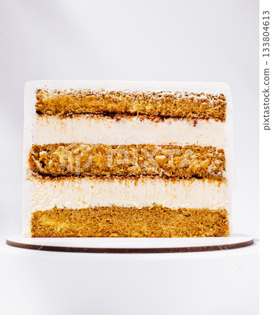 Delicious layered cake with creamy frosting displayed on a wooden board 133804613