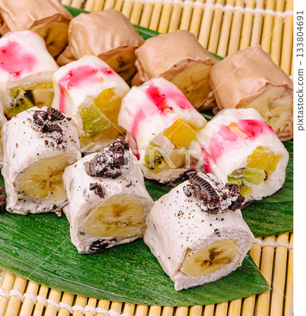 Delicious dessert rolls are arranged on a bamboo mat Delicious dessert rolls are arranged on a bamboo mat 133804691