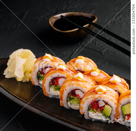 Delicious sushi rolls served with ginger and soy sauce on a black plate 133804704