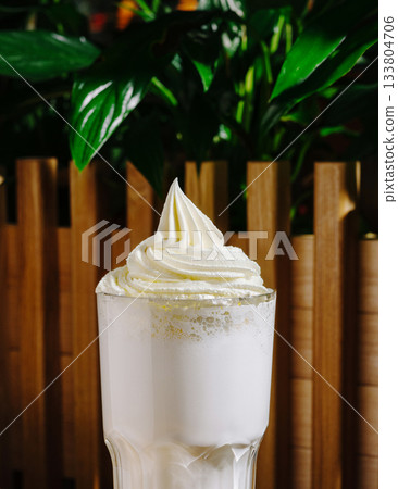 Whipped cream topped drink served in a glass against a green backdrop 133804706