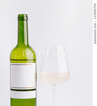 Elegant green wine bottle beside a clear glass of white wine 133804709