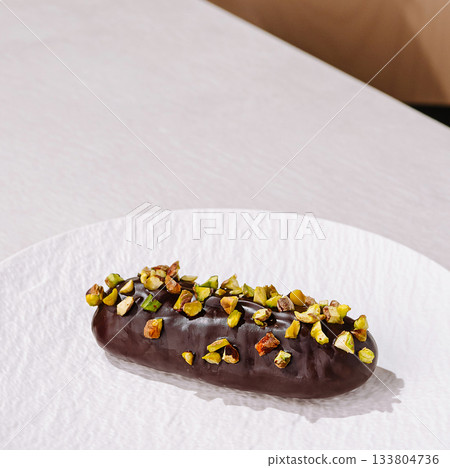 Delicious dessert with chocolate and pistachios on a white plate Delicious dessert with chocolate and pistachios on a white plate 133804736