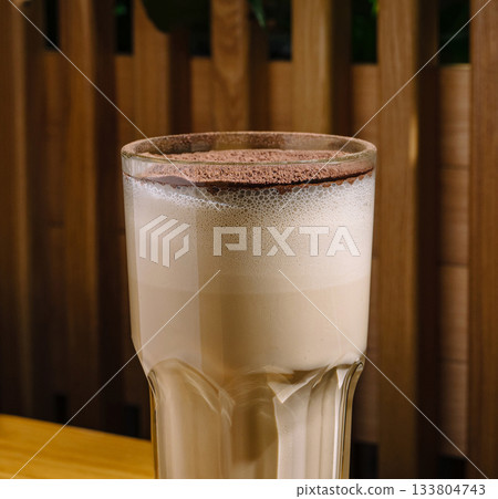 Delicious coffee latte topped with chocolate foam in a cozy cafe setting Delicious coffee latte topped with chocolate foam in a cozy cafe setting 133804743