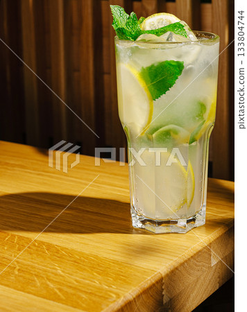 Mojito with mint and lime served on a wooden table in a casual setting Mojito with mint and lime served on a wooden table in a casual setting 133804744