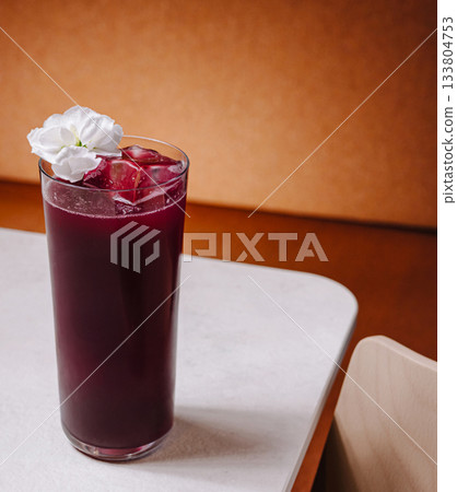 Refreshing drink served in a tall glass with flower decoration on a table Refreshing drink served in a tall glass with flower decoration on a table 133804753