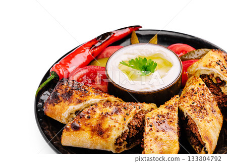 Delicious pastrama rolls served with yogurt and fresh vegetables on a plate 133804792