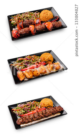 Grilled meat and seafood platter with sides served on black plates 133804827