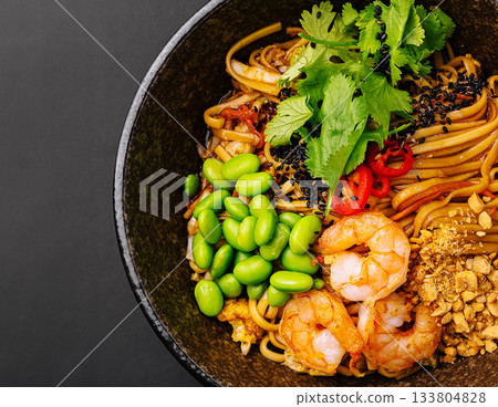 Delicious shrimp stir-fry with vegetables and noodles in a dark bowl Delicious shrimp stir-fry with vegetables and noodles in a dark bowl 133804828