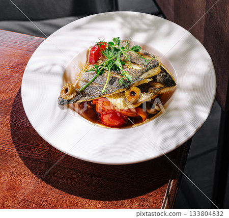 Freshly cooked fish dish with vegetables on a wooden table Freshly cooked fish dish with vegetables on a wooden table 133804832