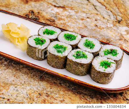 Fresh green sushi rolls served on a wooden plate with ginger slices Fresh green sushi rolls served on a wooden plate with ginger slices 133804834