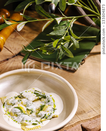 Fresh pasta dish served with creamy sauce and herbs on a rustic wooden table Fresh pasta dish served with creamy sauce and herbs on a rustic wooden table 133804873