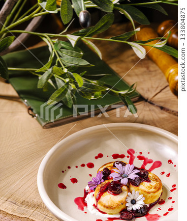 Delicious dessert with flowers and berry sauce on a rustic wooden table Delicious dessert with flowers and berry sauce on a rustic wooden table 133804875