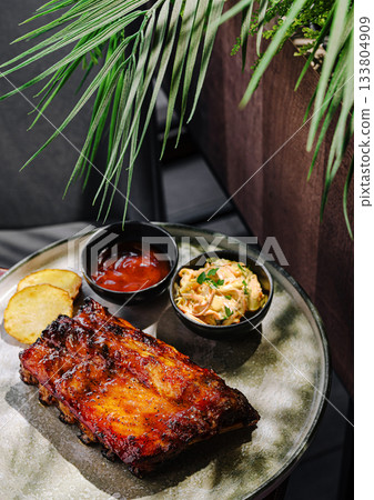 Delicious barbecue ribs served with sides in a modern dining setting Delicious barbecue ribs served with sides in a modern dining setting 133804909