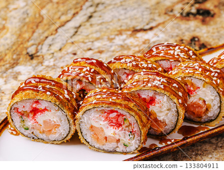 Delicious crispy sushi rolls served with sauce and sesame seeds 133804911