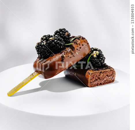 Brownie popsicle topped with blackberries on a white plate 133804933