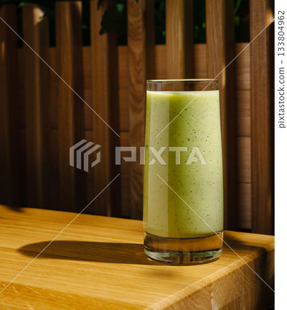 Refreshing green smoothie served in a tall glass on wooden table 133804962