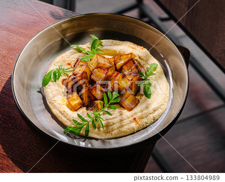 Delicious roasted vegetables on creamy hummus served in modern setting 133804989
