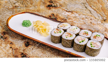 Delicious sushi rolls served on a sleek plate with wasabi and ginger Delicious sushi rolls served on a sleek plate with wasabi and ginger 133805002