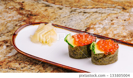 Delicious sushi rolls topped with fish roe and garnished with ginger Delicious sushi rolls topped with fish roe and garnished with ginger 133805004