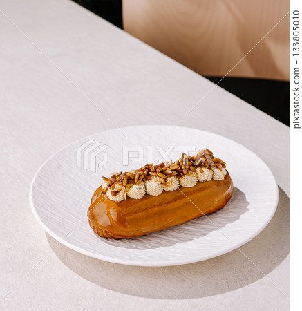 Creative eclair with caramel topping placed on a white plate 133805010