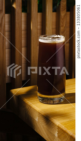 Cold brew coffee served in a clear glass on a wooden table Cold brew coffee served in a clear glass on a wooden table 133805061