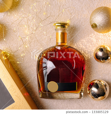 Elegant bottle of cognac surrounded by holiday decorations and warm lights 133805129