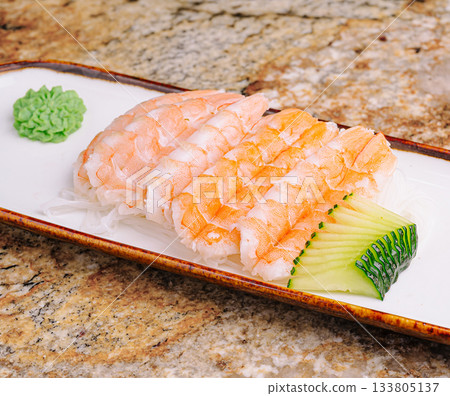 Fresh shrimp sushi served with wasabi and cucumber on a stone surface Fresh shrimp sushi served with wasabi and cucumber on a stone surface 133805137