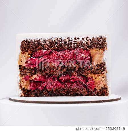 Delicious chocolate cherry cake slice revealed with creamy frosting Delicious chocolate cherry cake slice revealed with creamy frosting 133805149