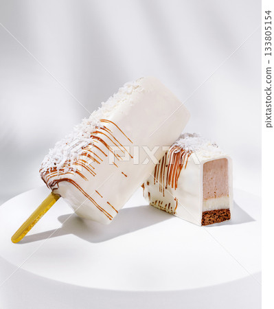 Delicious frozen dessert with creamy coating and chocolate layer on white plate Delicious frozen dessert with creamy coating and chocolate layer on white plate 133805154