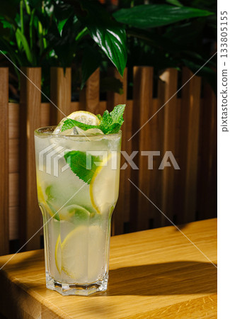 Refreshing mojito served in a tall glass with mint and lime on a wooden table 133805155