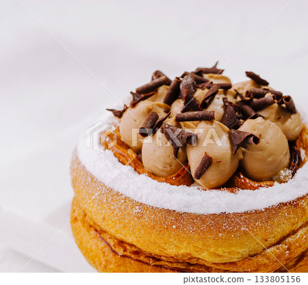 Delicious pastry dessert topped with creamy chocolate and cocoa curls Delicious pastry dessert topped with creamy chocolate and cocoa curls 133805156