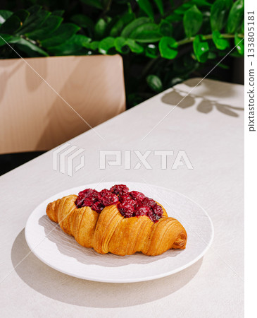 Delicious croissant topped with berry compote on a clean table Delicious croissant topped with berry compote on a clean table 133805181