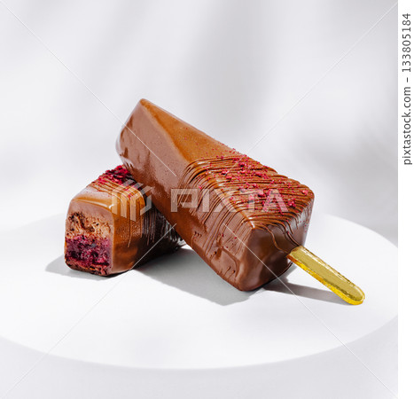 Delicious chocolate popsicle with raspberry filling on a white plate 133805184